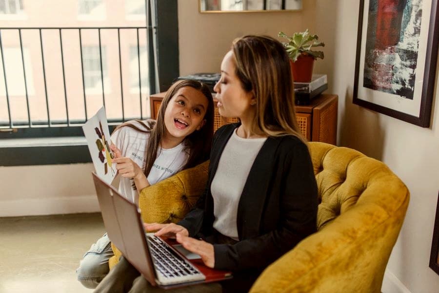 A girl showing her drawing to her mother, who is smiling back at her